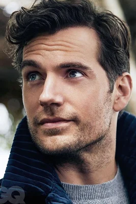 Henry Cavill en pull gris et veste en velours, avec un filigrane GQ.