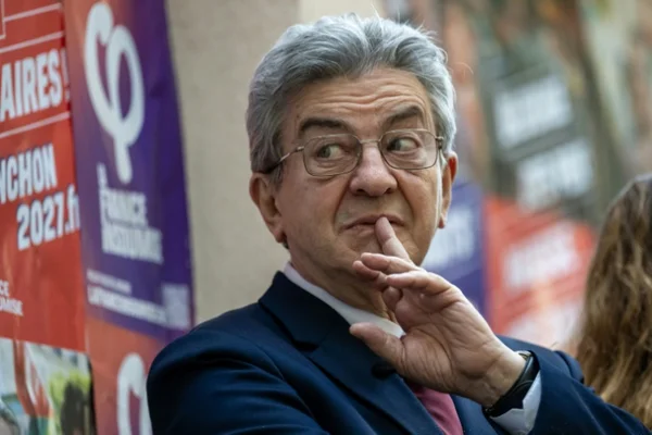 Jean-Luc Mélenchon s'adressant à des militants derrière des affiches de campagne.