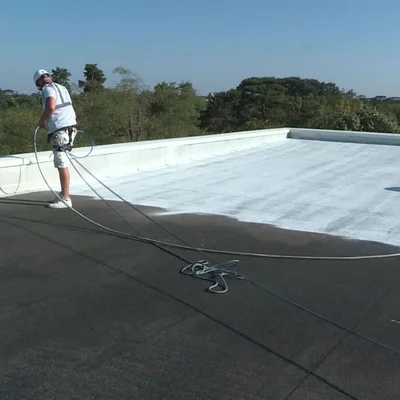 Un ouvrier applique une peinture blanche réflective sur un toit plat pour réduire la température.