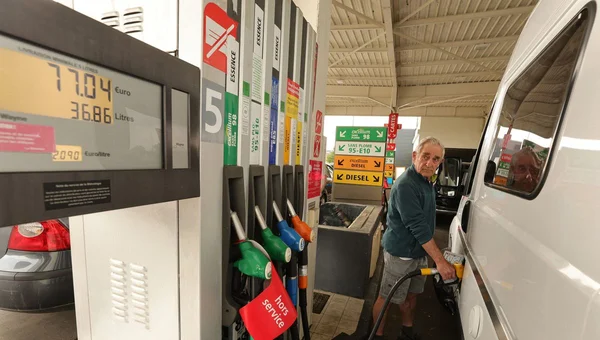 Vacancier faisant le plein à une station-service, illustrant l'offre de 50 euros d'essence.