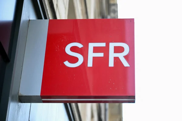 Enseigne rouge SFR sur un bâtiment, emblème de l'opérateur en cours d'acquisition.