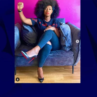 Assa Traoré posant sur un canapé bleu, poing levé, pour une campagne publicitaire.