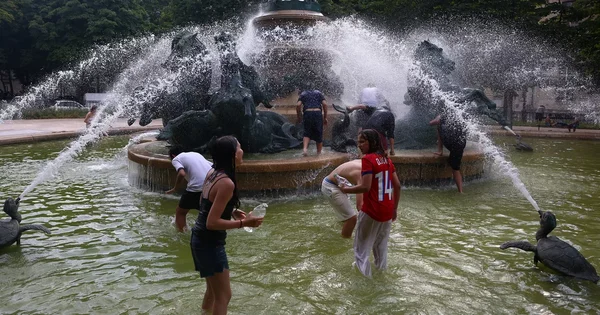 Des personnes se rafraîchissent dans une fontaine lors d'une canicule.