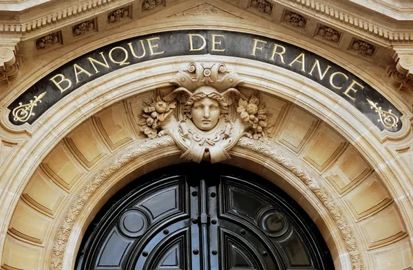 Porte d'entrée richement décorée de la Banque de France, avec une tête sculptée en clé de voûte.