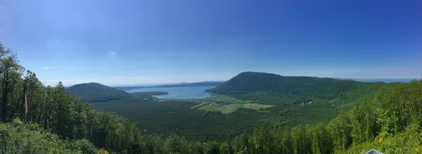 Panorama du lac de Vico entouré de collines et de forêts.