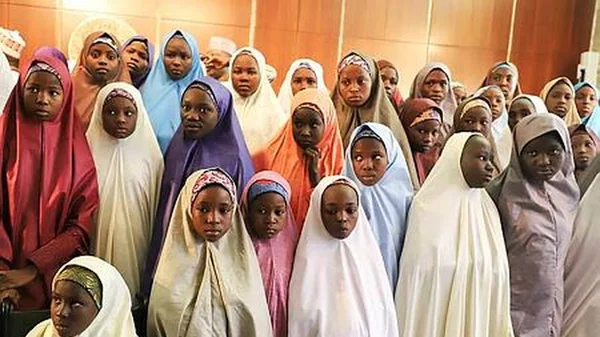 Des jeunes filles en hijab rassemblées à l'intérieur.