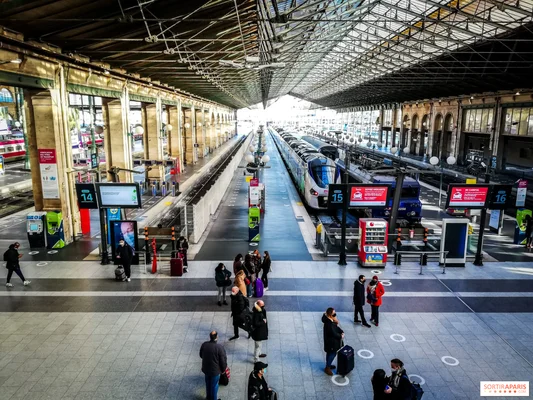 Quai de la Gare du Nord à Paris, avec voyageurs et train arrivant sous verrière.