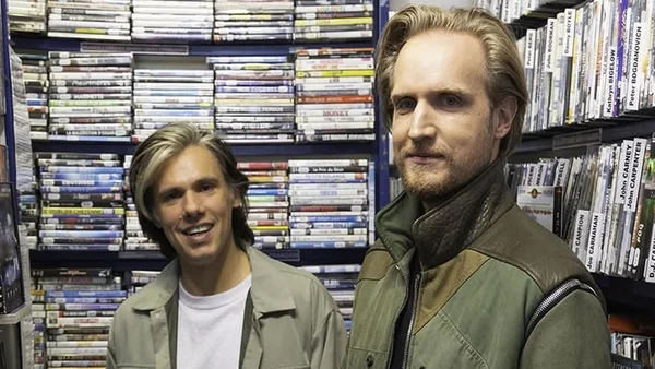 Orelsan et David Tomaszewski dans un vidéo-club, entourés de DVD.