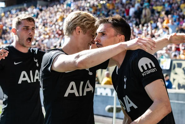 Des joueurs de Tottenham Hotspur célébrant un but, maillots noirs, devant un stade plein.
