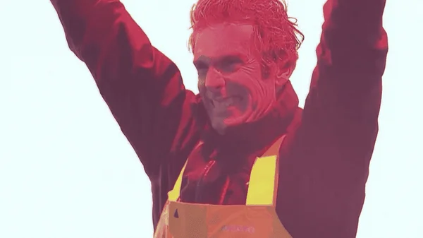 Charlie Dalin levant les bras, image avec une dominante rouge.