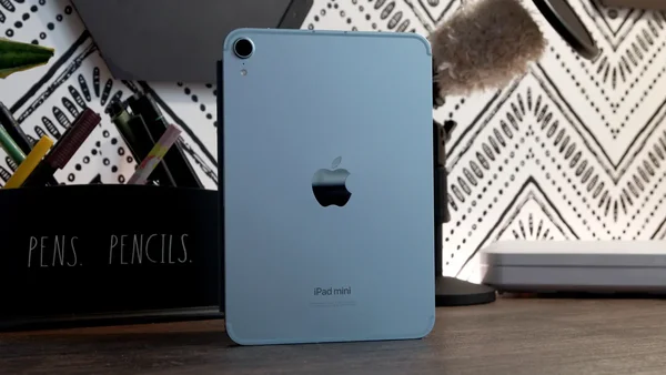 iPad mini bleu sur un bureau en bois à côté d'un pot à crayons.