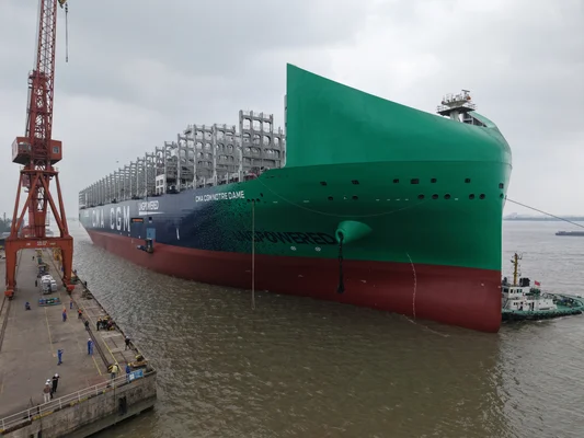 Le CMA CGM Notre-Dame amarré au Havre, avec une grue rouge et un remorqueur.