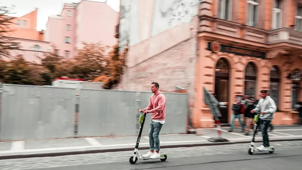 Utilisateurs de trottinettes en libre-service circulant dans une rue de Bruxelles.