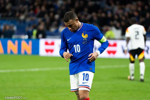 Kylian Mbappé, maillot des Bleus, ajuste sa tenue sur le terrain.