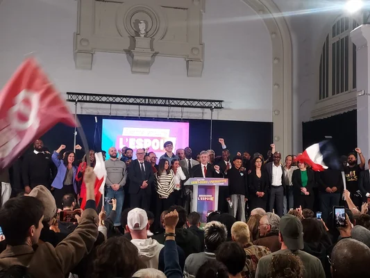Meeting de Jean-Luc Mélenchon à Saint-Denis : ambiance de campagne avec drapeaux et le mot « L'ESPOIR » sur l'écran.