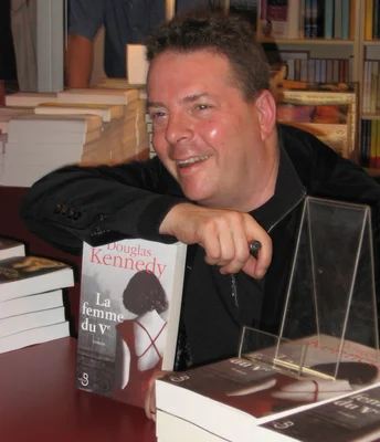 Douglas Kennedy, souriant, présente son roman 'La femme du Ve' lors d'une séance de dédicace.