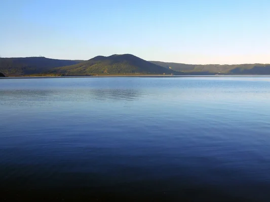 Le lac de Vico, plan d'eau paisible entouré de collines boisées.