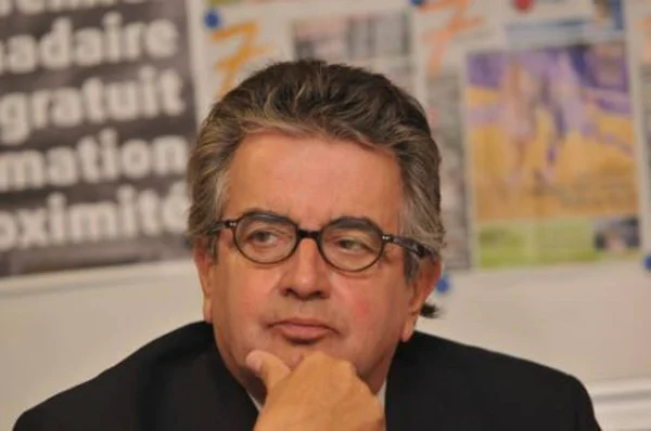 Alain Claeys dans une pose méditative, dans un environnement de travail.
