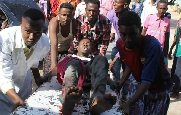 Des civils transportant un blessé sur une civière dans les rues de Mogadiscio après les affrontements.