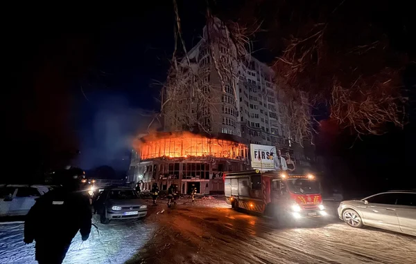 Pompiers intervenant sur un immeuble en feu à Kiev, rue enneigée, après une attaque russe.