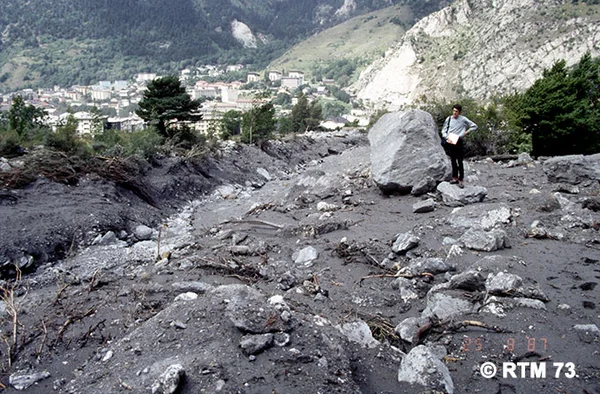 Lave torrentielle dans le torrent de Saint-Antoine à Modane, avec une personne observant les dégâts.