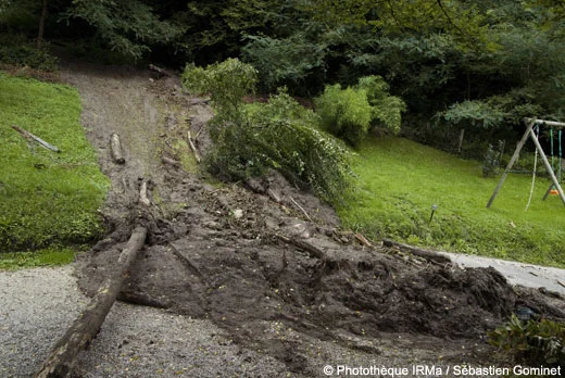 Coulée de boue dans un jardin à Aiguebelette-le-Lac, avec des arbres déracinés et des débris.