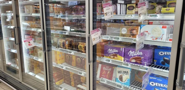 Rayon de glaces dans un supermarché, avec des marques populaires comme Milka et Oreo.