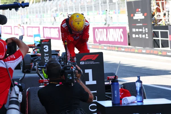Lewis Hamilton célèbre sa victoire à Barcelone, debout sur sa Ferrari, mains jointes devant le panneau numéro 1.