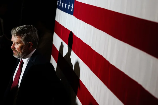 Thomas Massie devant un drapeau américain, ombre portée sur les bandes.