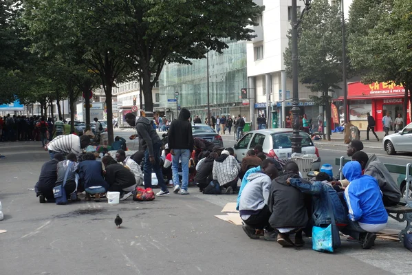 Rassemblement informel de personnes dans une rue, évoquant la situation des sans-papiers en France.