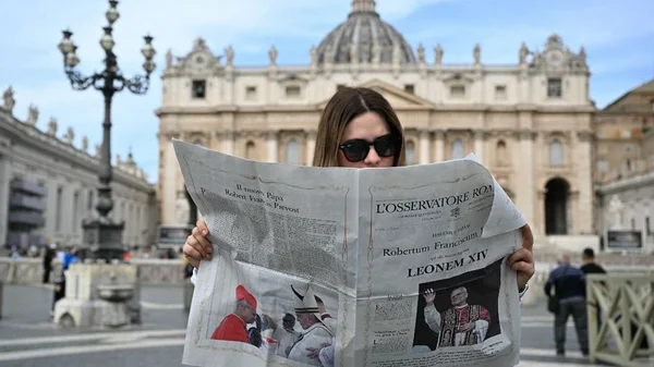 Une fidèle lisant L'Osservatore Romano après l'élection du pape Léon XIV, place Saint-Pierre.