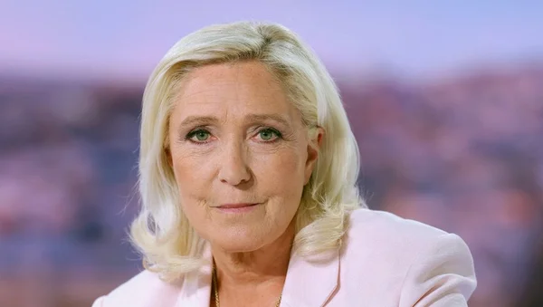 Portrait de Marine Le Pen souriant, veste rose clair.