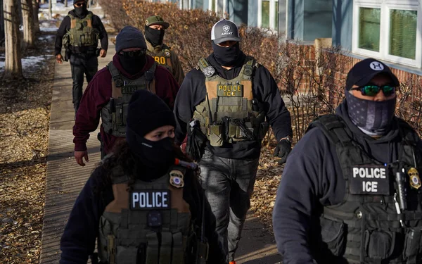 Agents de l'ICE en patrouille, portant des gilets tactiques marqués.