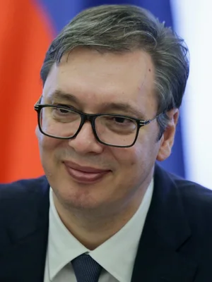 Aleksandar Vučić en 2019, souriant en costume sombre.