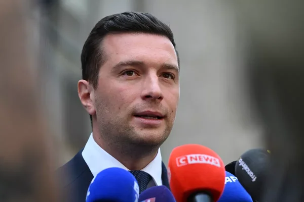 Jordan Bardella s'exprime lors d'une conférence de presse, devant un bouquet de micros dont celui de CNews.