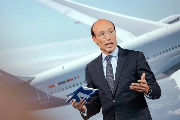 Anko Van der Werff lors d'une présentation, avec un livret Airbus et un écran montrant un avion.