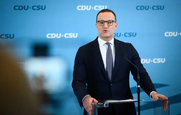 Un député conservateur allemand prenant la parole lors d'une conférence de presse, avec le logo CDU-CSU en arrière-plan.