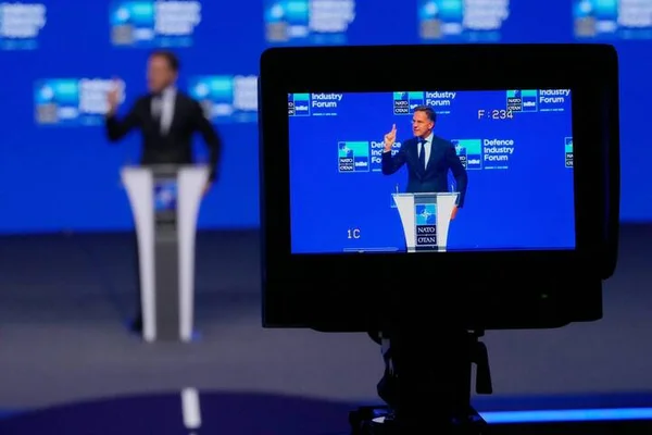 Intervenant au Forum de l'industrie de défense de l'OTAN, vu à travers un moniteur.