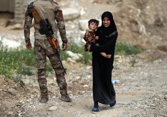 Scène de détresse en zone de conflit irakienne : une femme et son enfant croisent un soldat.
