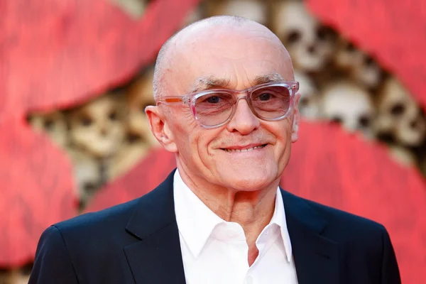 Portrait d'un acteur du film « Ink » dans une ambiance sombre, devant un fond rouge à motifs de crânes.