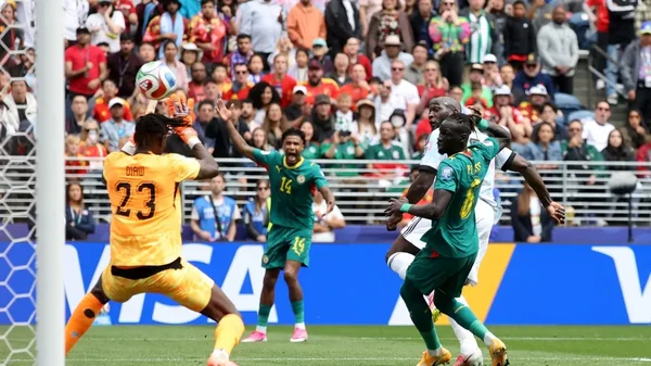 Un gardien de but plonge pour capter le ballon lors d'un match de Coupe du monde impliquant une sélection africaine.