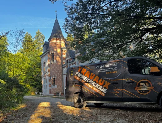 Un fourgon de travaux pour la fibre optique stationné devant un château en brique, illustrant le contexte des chantiers d'installation.