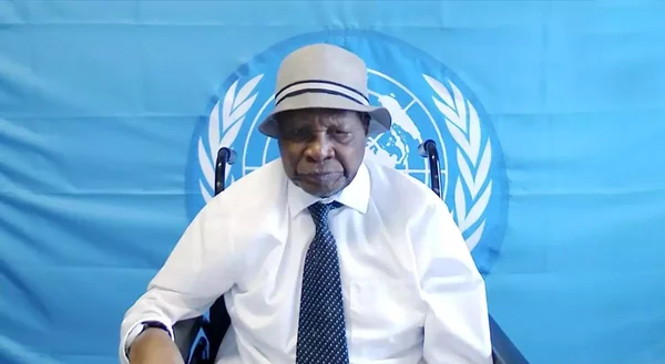 Félicien Kabuga, coiffé d'un fedora clair, assis devant le drapeau des Nations Unies.