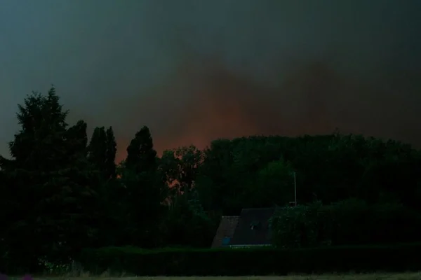 Lueur de l'incendie dans le ciel nocturne au-dessus de la forêt de Fontainebleau.