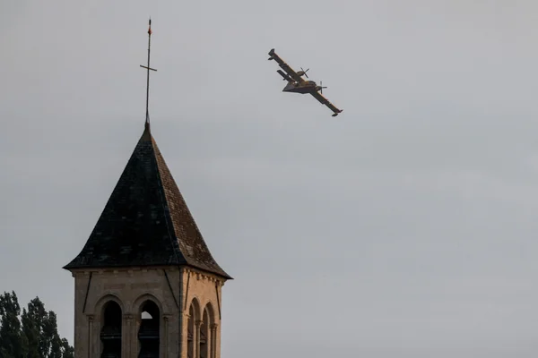 Un Canadair CL-415 survolant un clocher d'église lors des opérations de lutte contre l'incendie de Fontainebleau.