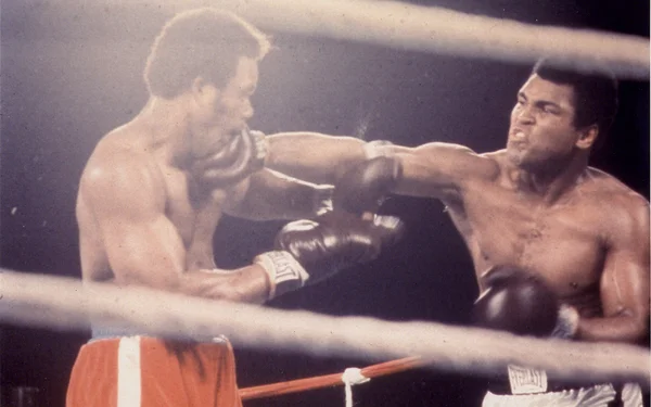 Combat de boxe vintage entre Muhammad Ali et Joe Frazier, Ali frappant Frazier au visage.