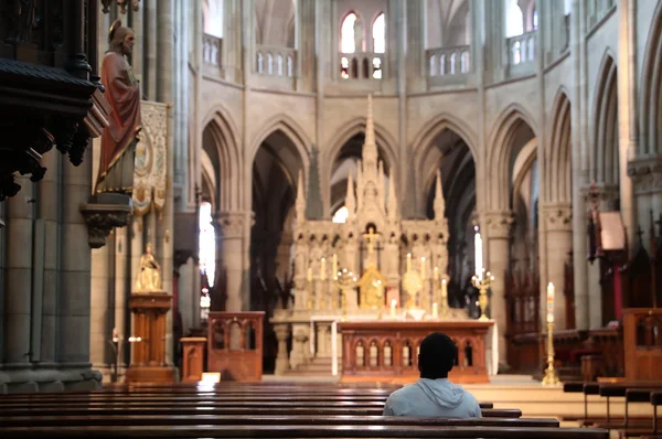 Intérieur de l'église Saint-Étienne de Mulhouse : un fidèle en prière dans la nef gothique.