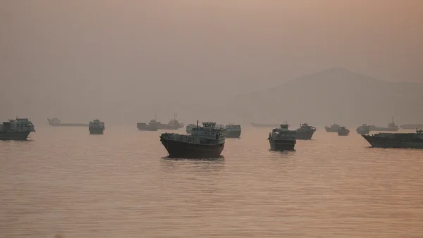 Navires ancrés dans un port brumeux, illustrant l'activité maritime dans la région.
