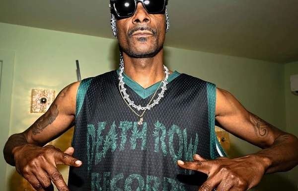 Snoop Dogg arborant un maillot Death Row Records et pointant le logo.