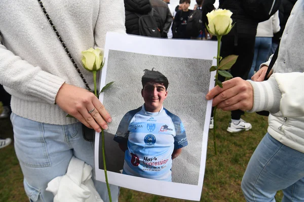 Hommage à Thomas : des participants tenant son portrait entouré de roses blanches.